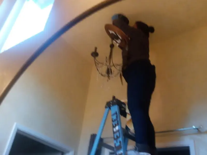 Electrician installing a chandelier in a CaÃÂ±on City residence